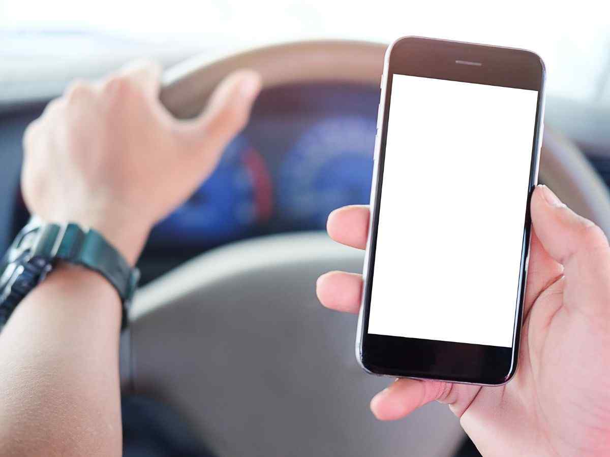Uso de celular ao volante penalidade motorista segurando celular enquanto dirige.