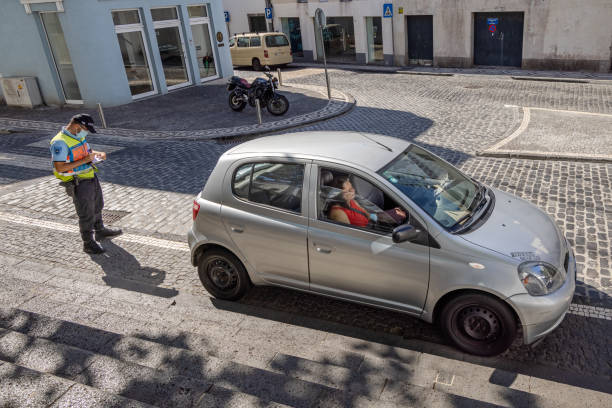 Carro estacionado em local proibido recebendo multa de agente de trânsito.