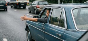 Sinalização manual: Braço estendido à esquerda pelo motorista, alertando outros veículos da intenção.