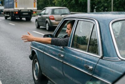 Sinalização manual: Braço estendido à esquerda pelo motorista, alertando outros veículos da intenção.